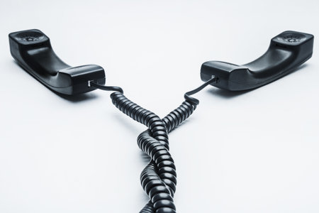 Black telephone receiver with cable on white backgroundの写真素材