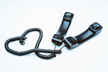 Black telephone receiver with cable on white backgroundの写真素材
