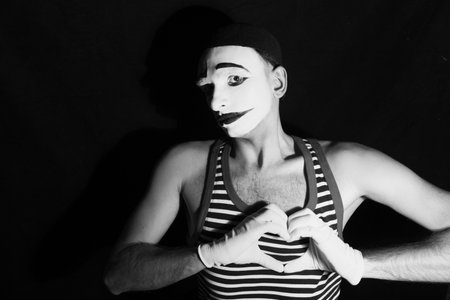 Portrait of sad mime with heart on black backgroundの写真素材