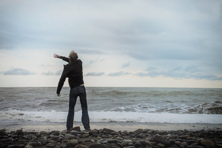 A young man standing on the sea shoreの写真素材
