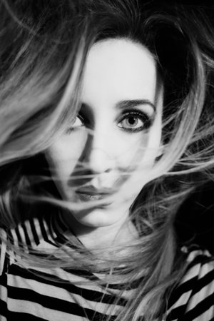 Monochrome Portrait of mysterious woman with her hair wrapped around her faceの写真素材