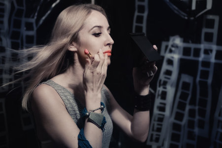 Young woman paints lips with pink lipstick. Studio portrait profileの写真素材