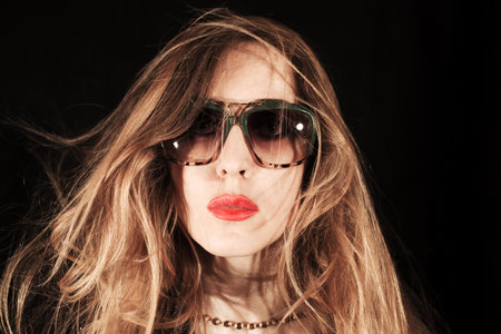 Face of  young woman dressed in sunglasses on a black backgroundの写真素材