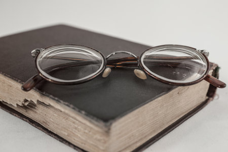 Old grandmother's glasses and a dilapidated book closeupの写真素材