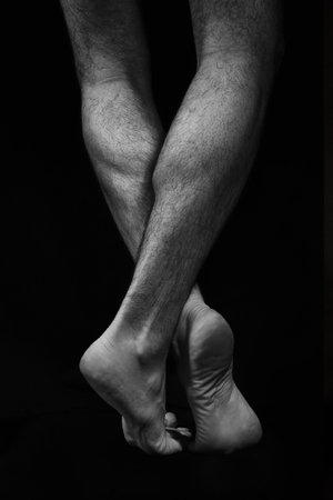 Naked muscular male legs on a black background. Contrast black and white photoの写真素材