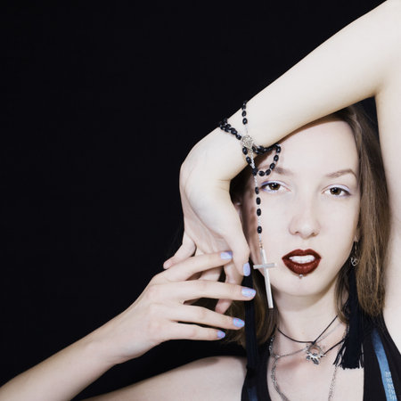 Portrait of a beautiful girl with Catholic beads on black backgroundの写真素材