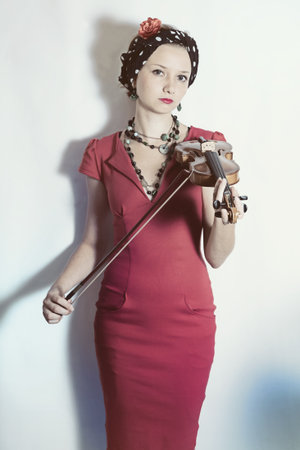Young violinist woman with violin in hands on a white background. Studio portraitの写真素材