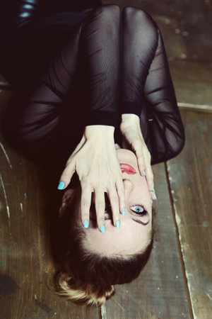 Young beautiful woman lies on the floor, covering  face with her handsの写真素材