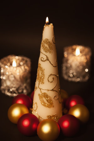 Greeting Christmas card with a burning candle and Christmas decorations on  black backgroundの写真素材