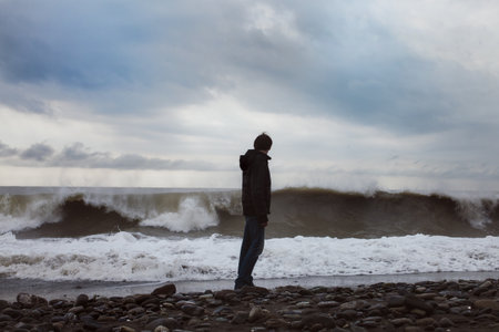 A young man standing on the sea shoreの写真素材