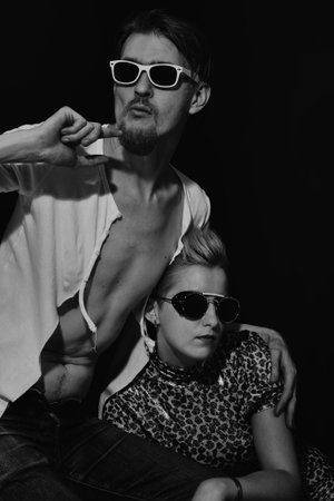 Stylish young man and woman wearing sunglasses on a black background. Fashion themeの写真素材