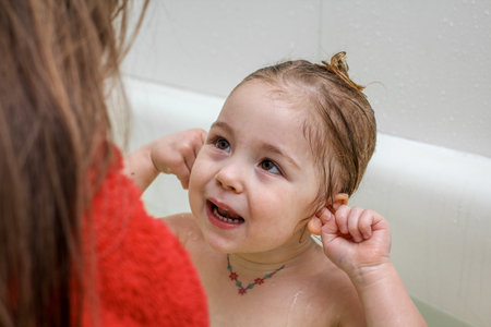 A little girl makes funny faces in the bath and she is very happyの写真素材