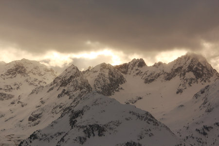 Warm sun rays break through winter clouds. Alps mountains.の写真素材