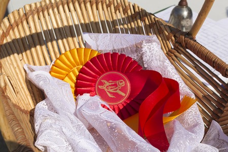 Award rosettes for winner in equestrian sport and horse show, red and yellow colors with ribbons in basketの写真素材