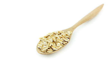 Close up Rolled oats (oat flakes) in a wooden spoon on white backgroundの写真素材