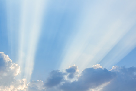 Clouds and a blue sky with a sunbeam shining through, evening time.の写真素材
