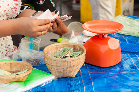 vendor counting money in hand before put in basket after saleの写真素材