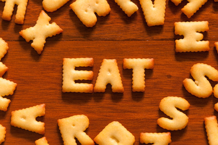 the word eat written with alphabet cracker on wooden tableの写真素材