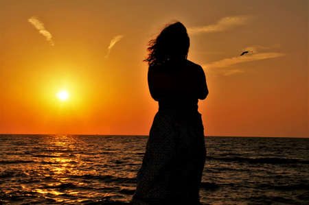 silhouette of a young woman by the sea at sunset
