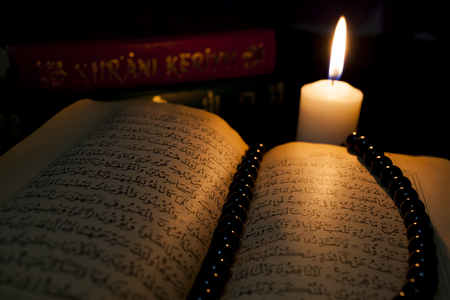 Quran books are illuminated by candle.の写真素材