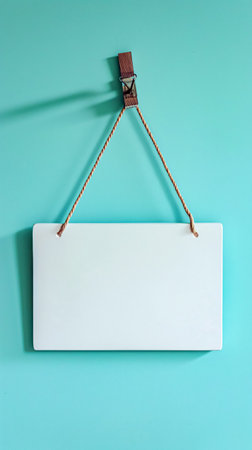 Blank sign hanging on a rope on a turquoise backgroundの素材