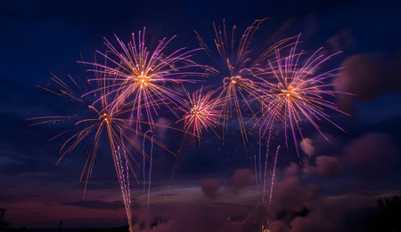 Vibrant fireworks display illuminating the dark night sky with bursts of purple and orange light, celebrating an eventの素材