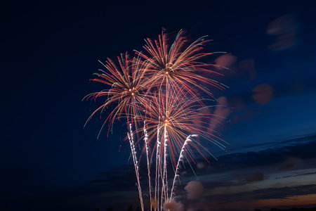 Spectacular fireworks burst across the deep blue evening sky, creating a dazzling light show for a festive celebrationの素材