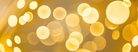 Abstract golden bokeh lights background, shimmering and glowing with warm yellow circles, perfect for festive and celebratory designsの素材