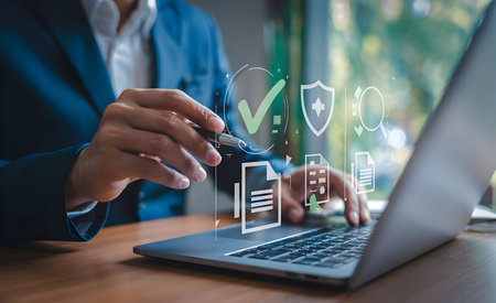 Businessman using laptop with security and data management icons, symbolizing verified digital processes, compliant online protection and approvalの素材