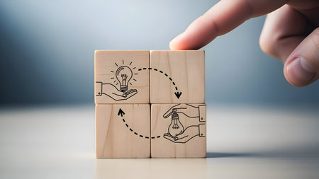 A hand interacting with wooden blocks illustrating a circular flow of ideas, concept development, innovation, and creative exchange in a collaborative business processの素材