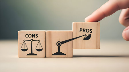 Pros outweighing cons, human finger pressing down on 'pros' wooden block on a conceptual balance scale, illustrating decision making and advantages.の素材