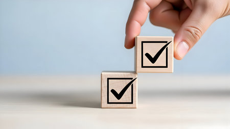 Hand placing a wooden block with a black checkmark symbol, signifying agreement, successful task completion, confirmation or positive vote on a light backdrop.の素材