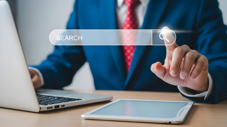 Business professional interacting with a digital interface projected from a laptop and tabletの素材