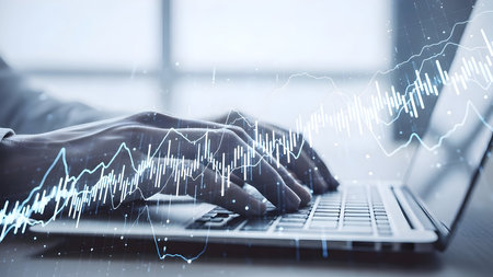 Hands typing on laptop with data visualization and stock market graphs overlaid on the screenの素材