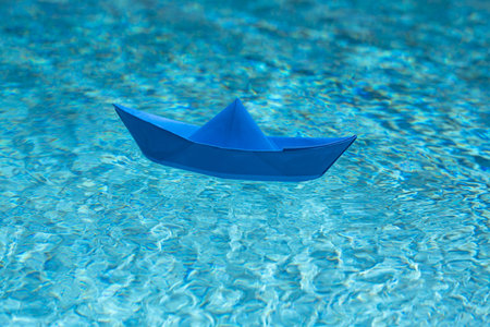 Paper boat in water. Paper boat sailing. Tourism and traveling, travel dreams vacation holiday, sailing adventure. Traveling adventure. Sail boat. Summertime vacation. Paper ship and ocean water.の写真素材