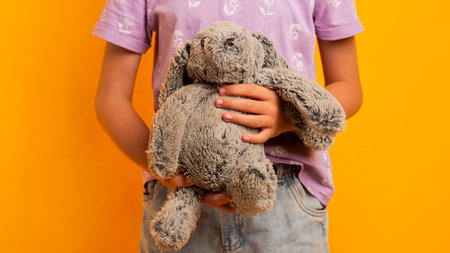 Kid with plush toy. Bunny toy in hand. Easter bunny toy. Bunny ears and Easter eggs. Easter bunny toy in hand. Holidays background. Season holidays.の写真素材