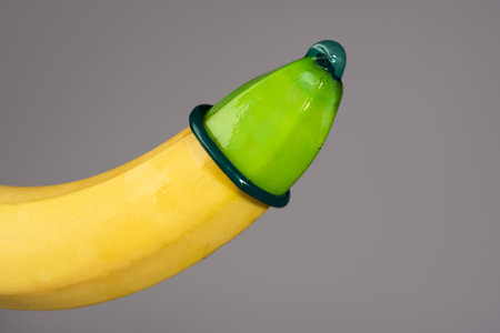 A yellow banana with a green tip and a green band around the middle.の写真素材