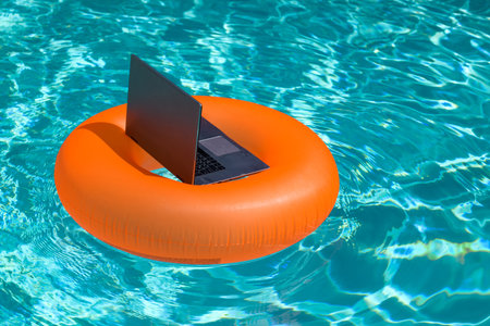 Summer business. Freelance style. Remote working in swimming pool. Summer travelling. Business at summer vacation. Laptop with blank screen. Summer vacation concept.の写真素材