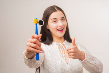 Stomatology. Dental hygiene. Dental equipment. Dental mirror. Straight white teeth. Stomatology equipment. Young smiling woman holding a toothbrush and dentistry mirror. Dental hygiene and oral care.の写真素材