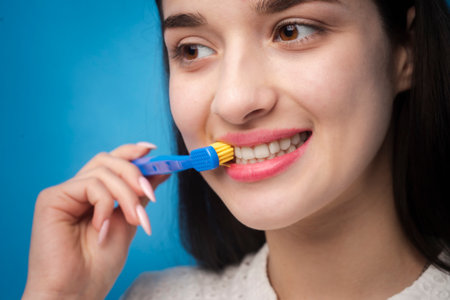 Toothbrush and teeth. Close up of woman mouth cleaning teeth. Dental wellness. Oral freshness. White, healthy teeth. Brushing action. Yellow bristles. Routine hygiene care.の写真素材