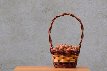 Hazelnuts in wicker basket on the background of gray wall.の写真素材