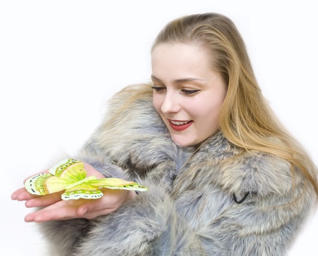 a girl in a fur coat by a cold winter holds a butterflyの写真素材