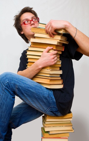 a student in horror holds a mountain of their textbooksの写真素材