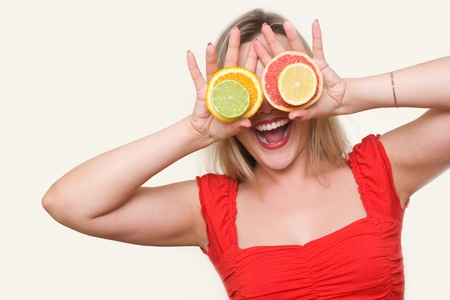 beautiful blond girl using citrus as glasses and smilingの写真素材