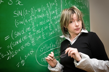 surprised teacher against the background of a green chalkboardの写真素材