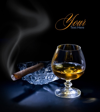 Glass of cognac with a cigar on dark sackgroundの写真素材