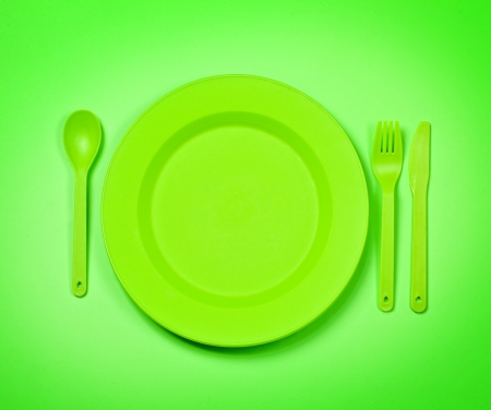 bright green  plastic disposable tableware, plates and forks, on bright green background の写真素材