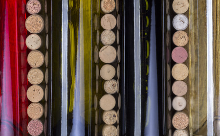 Glass bottle of wine with corks on wooden table backgroundの写真素材