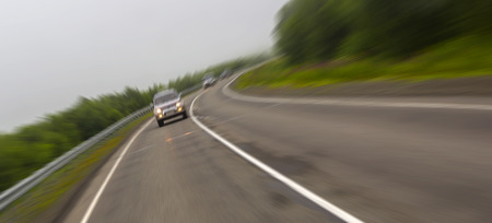 Car rides on a rural road that runs through the forestsの写真素材