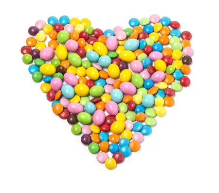 Colorful candies in the shape of heart on white background isolated with shadows top view
